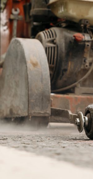 Close up and selective focus of the petrol powered road saw with dimond blade cutting asphalte road surface